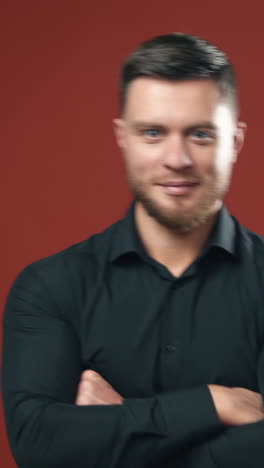 elegant male model in studio. confident businessman standing with his hands folded at his chest. vertical video
