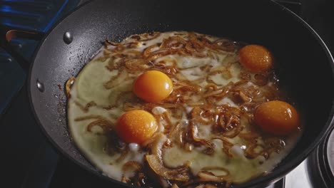 mezclar huevos fritos y cebolla en una sartén con una cuchara de madera, vista de cerca en la cocina de casa