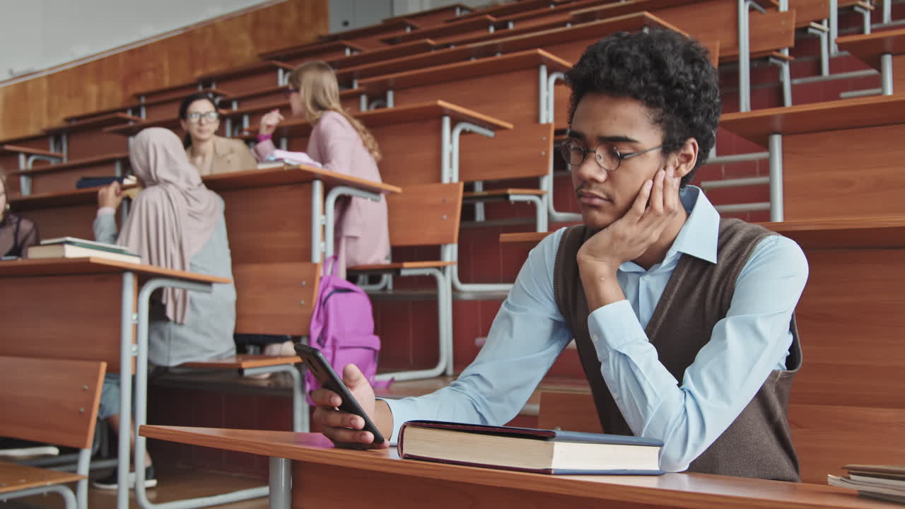 Young Mixed Race Student Scrolling through Smartphone during Lesson