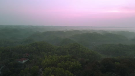 Birds-Eye-view-flying-over-green-hill-with-forest-at-day-in-Indonesia