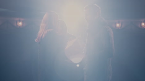 man and woman playing romantic scene near director actor and actress with scripts holding hands and speaking with each other while rehearsing romantic scene with director on stage in theater