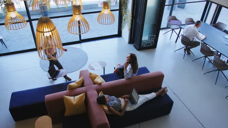 Overhead-View-Of-Modern-Open-Plan-Office-With-Staff-Working-Around-Table-And-Breakout-Seating-Area