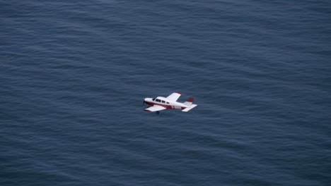 Vista-De-ángulo-Alto-Del-Pequeño-Avión-Que-Vuela-Sobre-El-Mar-Azul