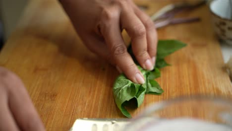close-up of hands chopping fresh basil leaves