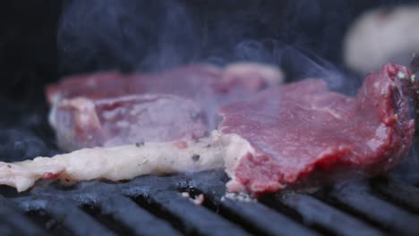 bbq 셰프는 느린 동작 4k에서 불타는 흡연 그릴에서 지방을 벗긴 고기 스테이크를 움직입니다.