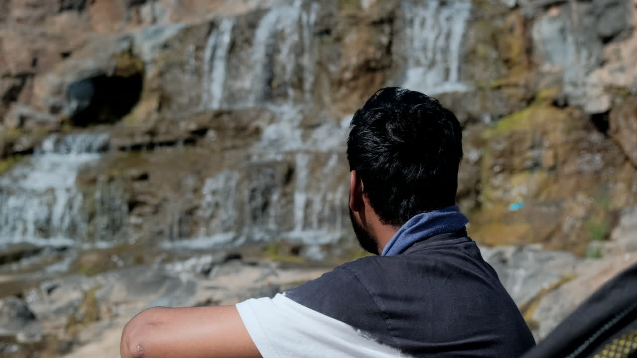 화창한 날에 폭포를 감상하는 남자의 뒷모습