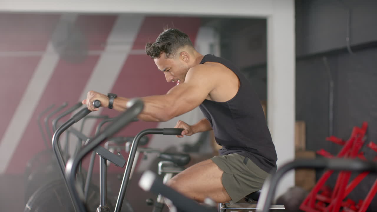Exercising on stationary bike, man focusing on intense cardio workout in gym