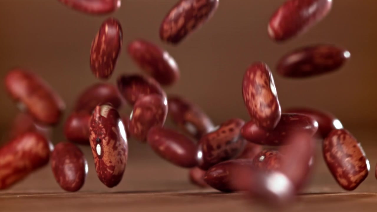 Red Kidney Beans Falling in Slow Motion onto a Wooden Surface