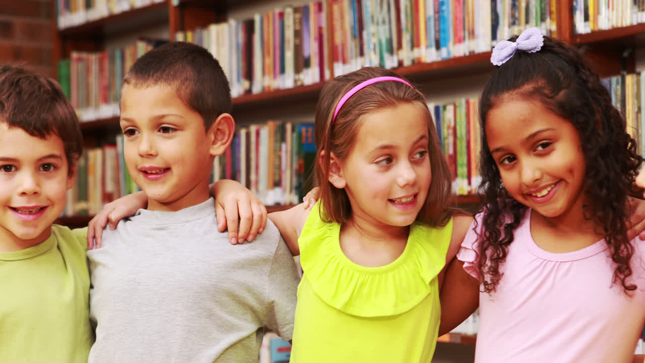 alumnos sonriendo a la cámara en la biblioteca