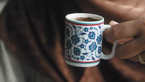 close-up of a hand holding a patterned coffee cup
