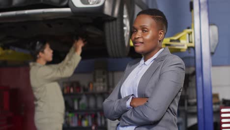 Video-of-happy-african-american-female-car-repair-shop-owner-looking-at-camera