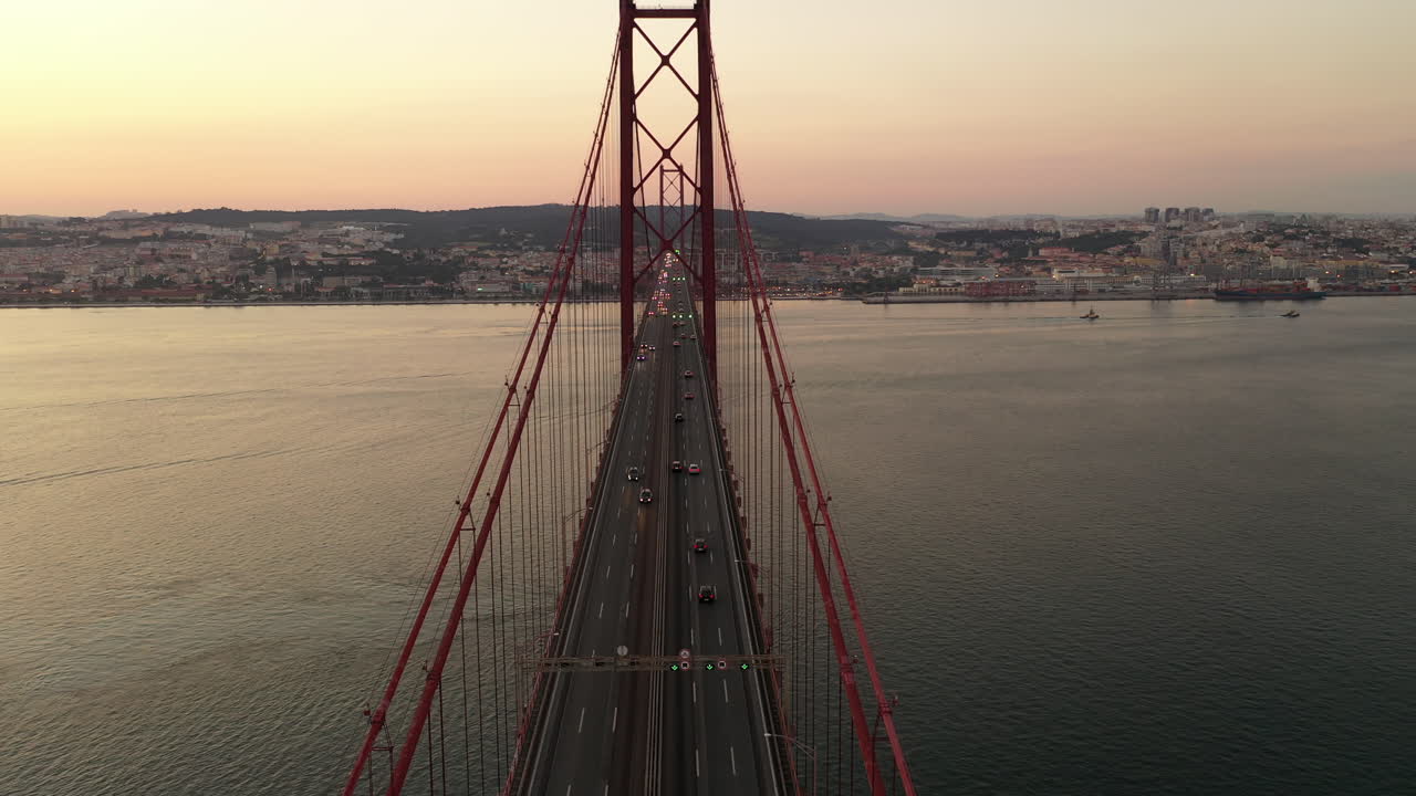 Vista aerea del traffico sul ponte sospeso 25 de Abril e sul fiume Tago verso lo skyline di Lisbona al tramonto, Portogallo.