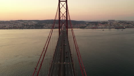 vista aérea del tráfico en el puente colgante veinticinco de abril y el río tajo hacia el horizonte de la ciudad de lisboa al atardecer, portugal