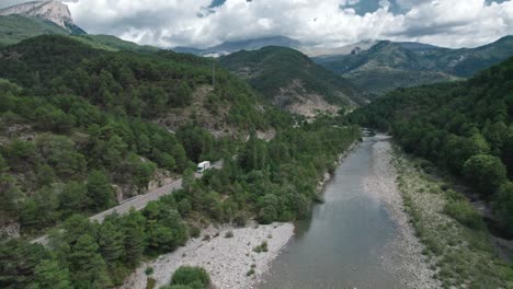 mountain river with a rocky bank, top view. green trees and a narrow path meander alongside.