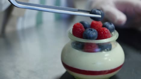 chef preparing a panna cotta dessert with raspberries and blueberries