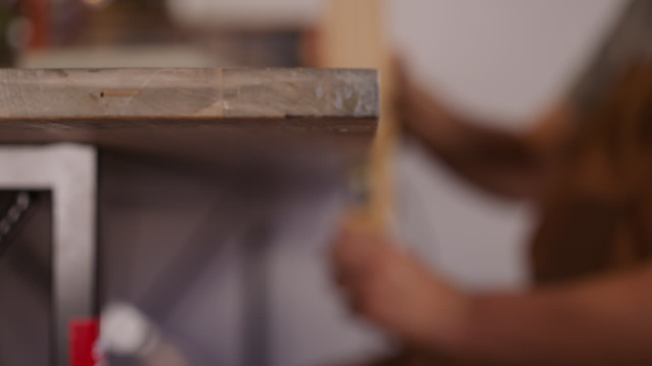 Worker removes wooden clamp from workbench at carpentry