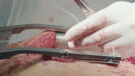 doctor cuts thread during operation. surgeon uses sterile scissors preparing chest for sewing up after successful coronary artery bypass graft surgery