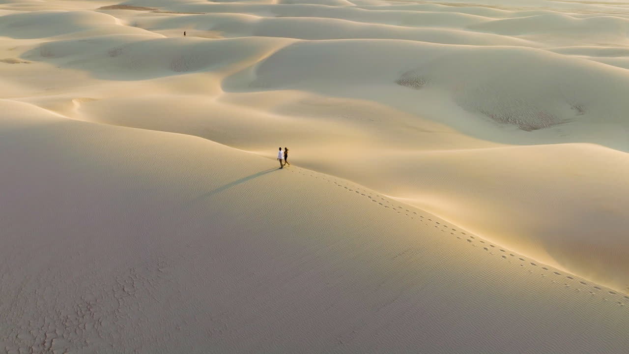 Coppia che cammina sulle dune di sabbia di Zahek lasciando impronte sull'isola di Socotra, Yemen - ripresa aerea