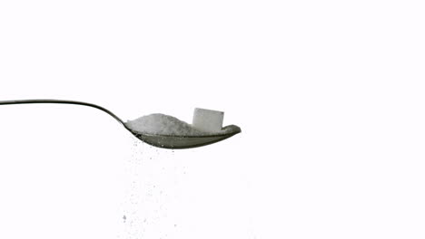 sugar spilling off spoon with sugar and sugar cube