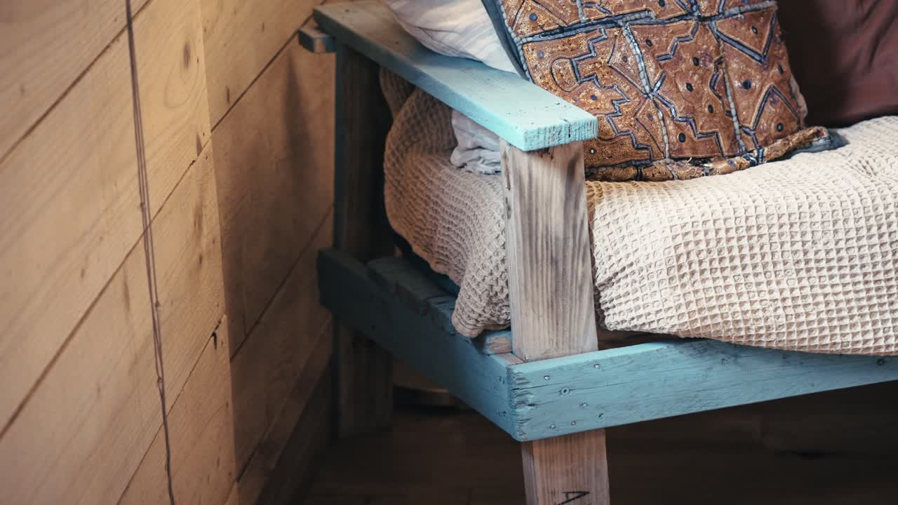 Cozy cabin featuring a blue pallet chair, symbolizing rustic charm and DIY comfort, earthy tones create a warm and inviting atmosphere, perfect for relaxation