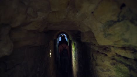 tourists walking exploring deep long underground rocky tunnel, roman sewers in medina, cadiz, spain