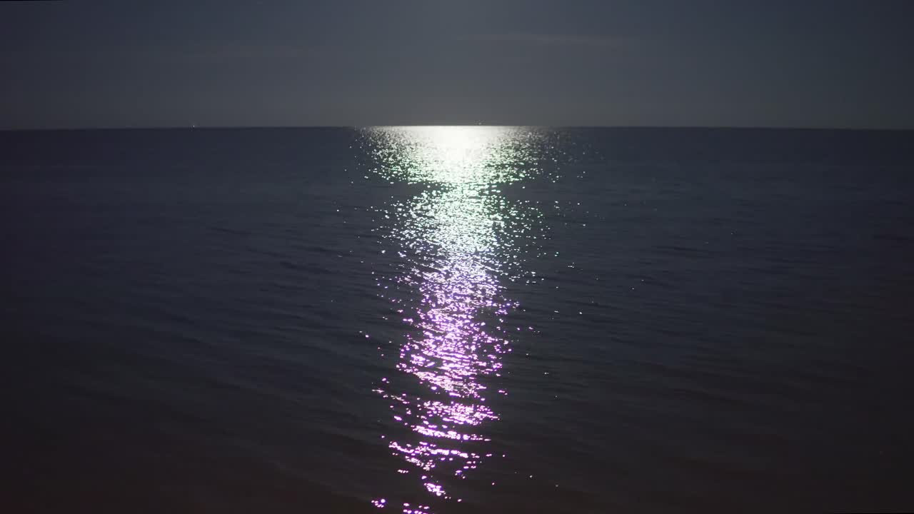 Still shot of a calm sea lit by a moonlight