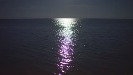 still shot of a calm sea lit by a moonlight