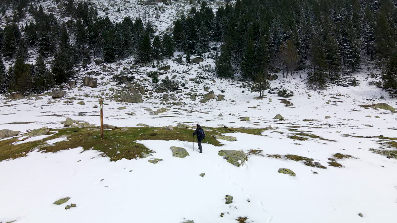 hombre adulto camina por la montaña a través de la nieve llegando a la señal de dirección en la cerdanya