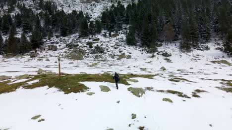 adult man walks on the mountain through the snow reaching the direction sign in la cerdanya