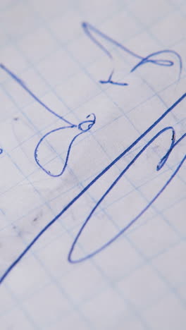 person writes words JUST DO IT in bad handwriting with modern pen on empty checkered paper sheet extreme close view