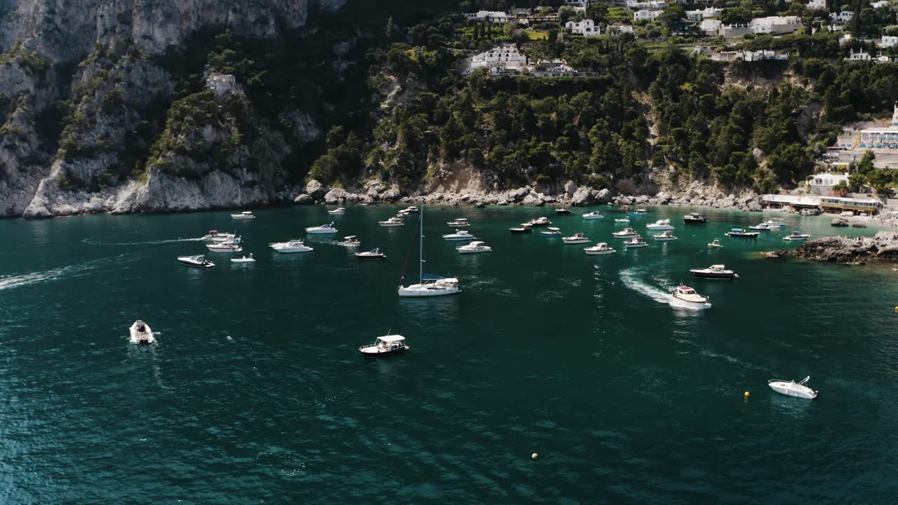 Orbiting aerial view of numerous boats safely moored in Italy's Marina Piccola shoreline