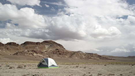 Alone-in-the-Nevada-Desert,-Tent-Camping-under-the-clouds-of-a-arid-summer-day,-Wide-with-mountains