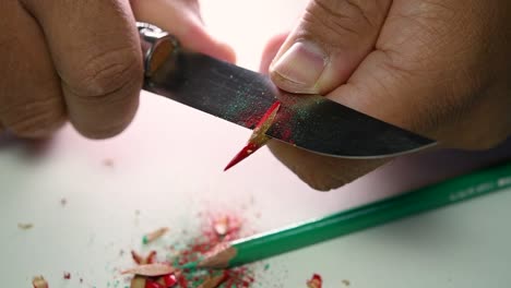 Footage-of-hands-slowly-sharpening-a-pencil-and-some-coloured-pencils-with-a-sharp-knife