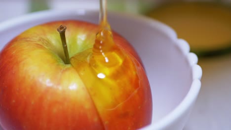 la miel curativa transparente amarilla se vierte en un arroyo en una manzana roja madura en un cuenco