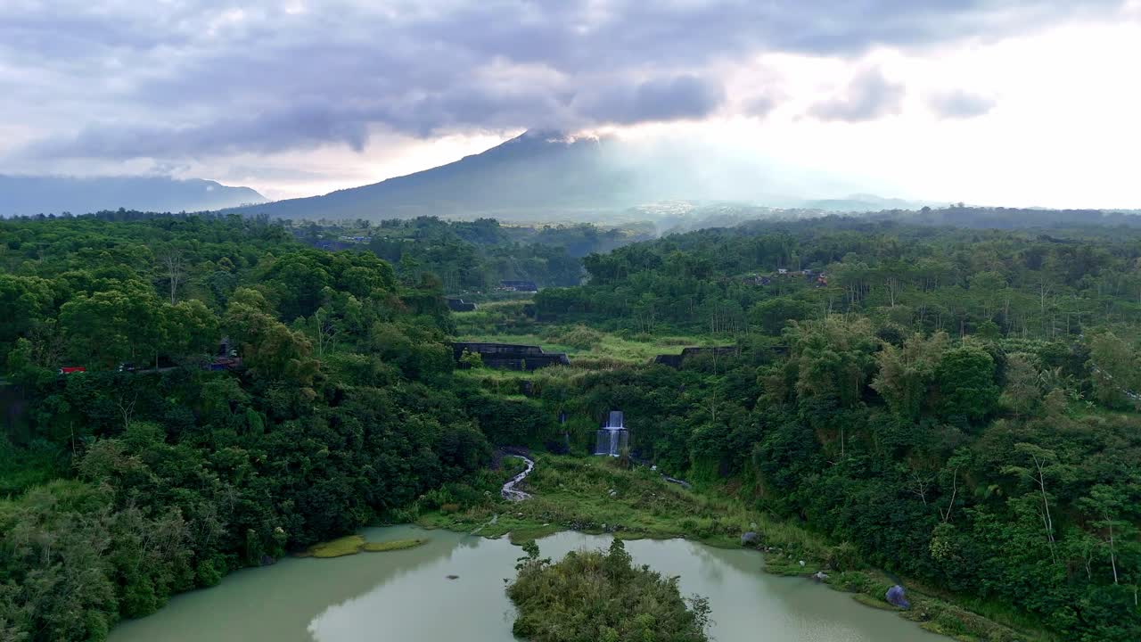 Aerial nature scenery of green rain forest and lake with mountain background. 4K drone view.
