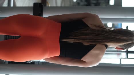 Athletic woman trains the back muscles in the gym, she pumps the main muscle groups. Girl swings her arms on the simulator. Beautiful caucasian woman in the gym