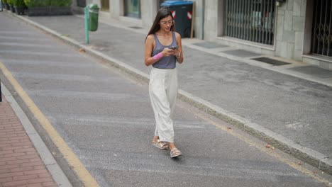 woman walking on city street using smartphone