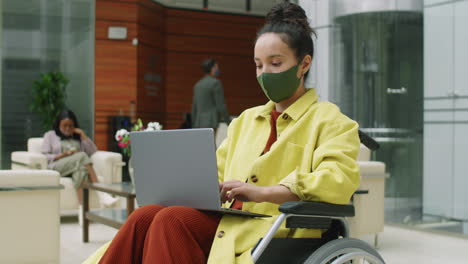 Masked-Businesswoman-Working-on-Laptop-in-Wheelchair