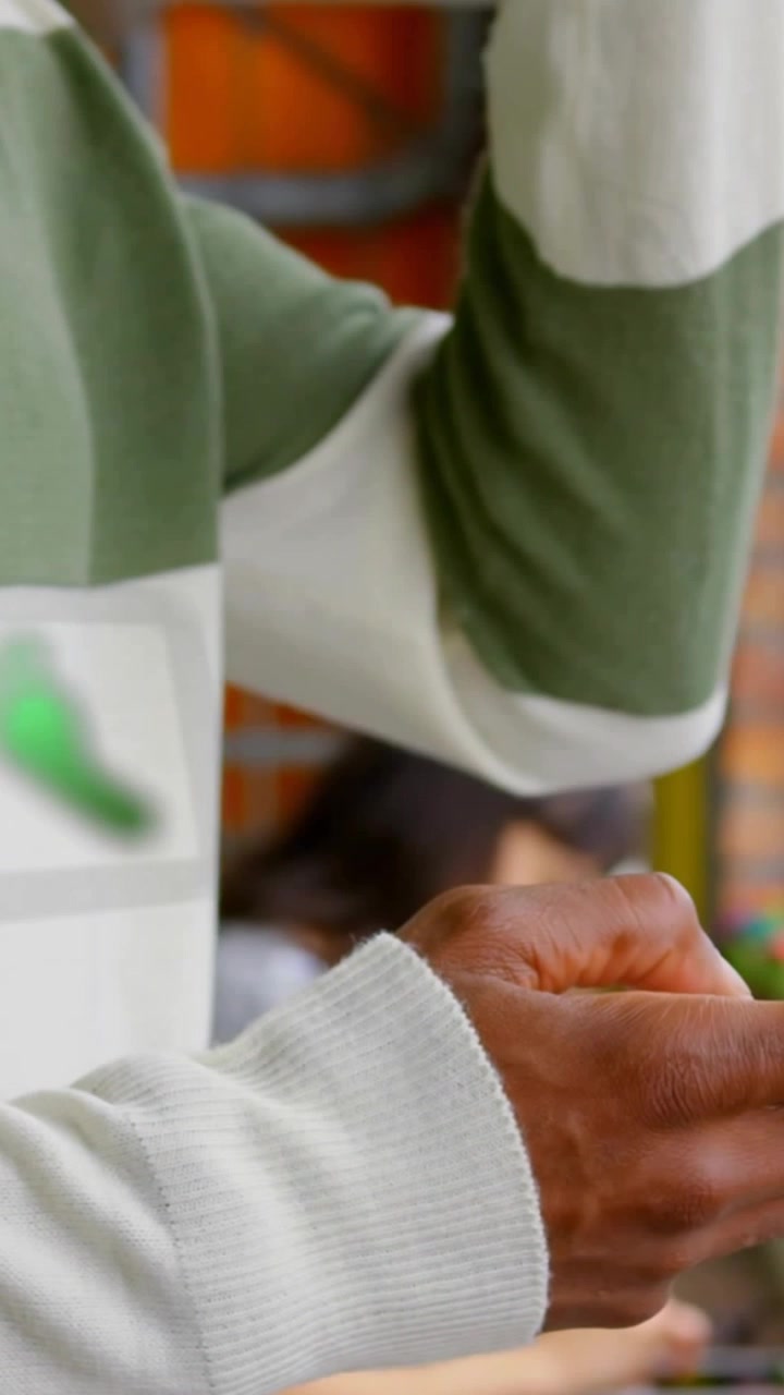 Vertical video: Man getting to-go cup in cafe, tilting cup to sip, UI icons flashing near forearm