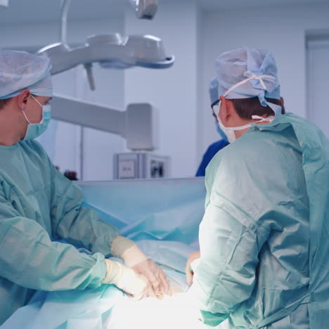 group of doctors perform an operation to a patient. surgeons in medical uniform and masks working in the operating room