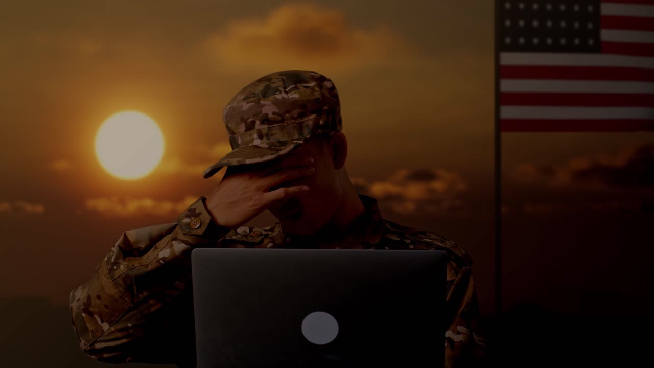 primer plano de un soldado asiático que usa una computadora portátil y tiene dolor de cabeza mientras está de pie con la bandera de los estados unidos, hora del atardecer