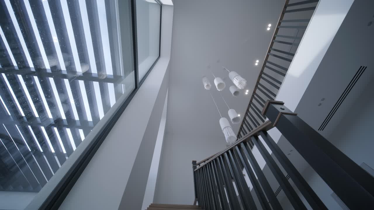 A high ceiling atrium with a large skylight floods the modern staircase and unique hanging lights with daylight