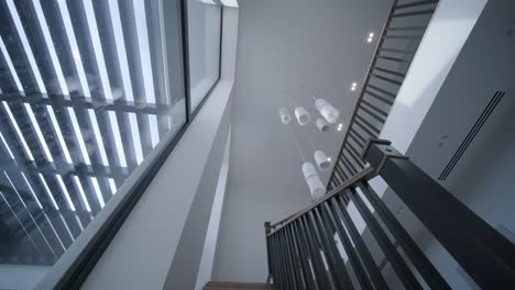 a high ceiling atrium with a large skylight floods the modern staircase and unique hanging lights with daylight