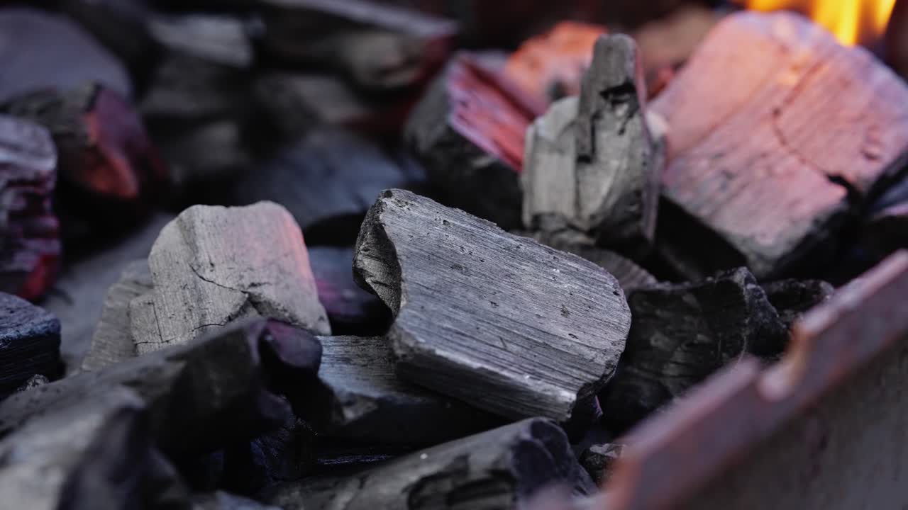 Charcoal ignites with sparks flying as flames build for outdoor cooking or grilling