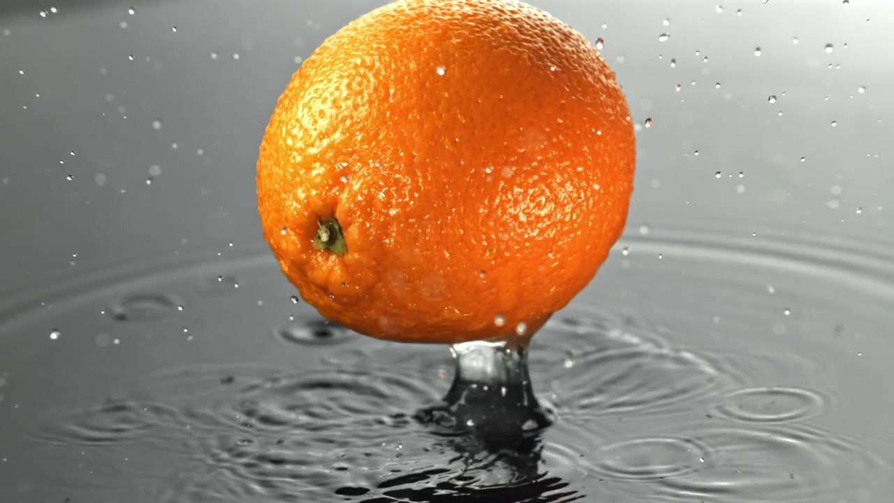 Frisk appelsin falder ned i vand i slowmotion