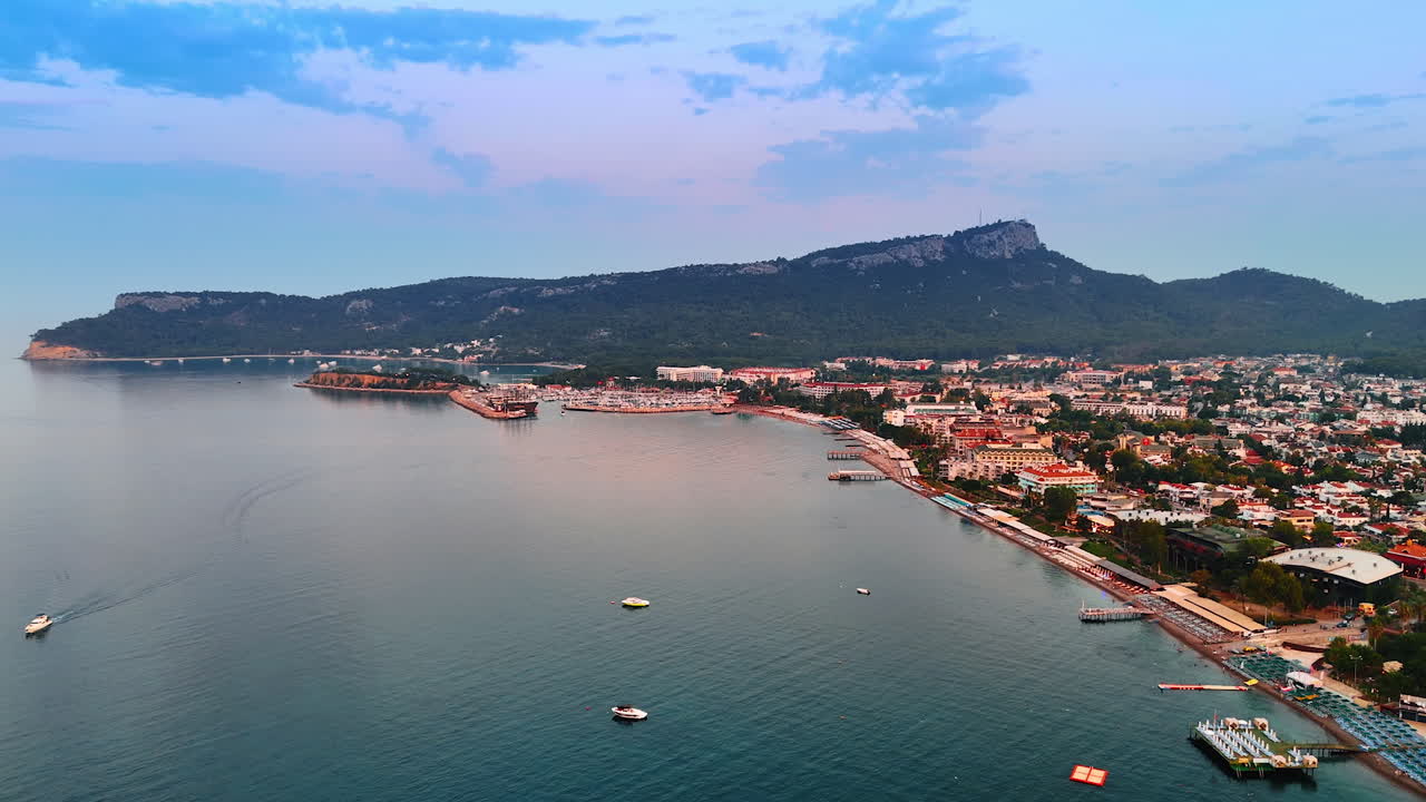 Few boats on the peaceful waterscape of the Mediterranean Sea near Kemer, Turkey. Verdant mountains surround the resort. Aerial view