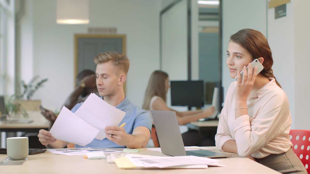 코워킹 스페이스에서  ⁇ 드폰으로 flirting 젊은 여성. 웃는 여성