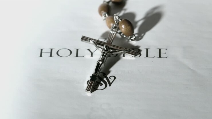 Rosary beads falling onto first page of holy bible