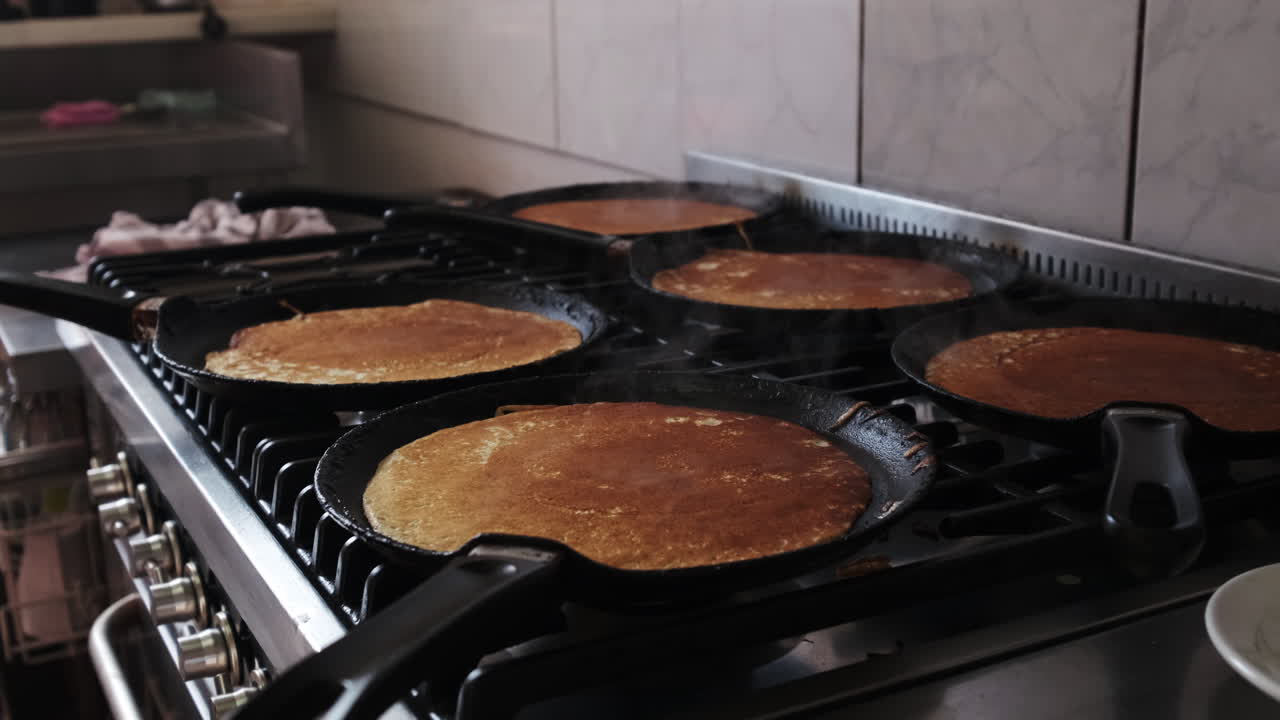 dolly hacia atrás sobre pankakes que se cocinan en las cacerolas de un horno de gas