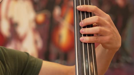 Hombre-Tocando-El-Contrabajo-Con-La-Mano-Izquierda-En-Un-Primer-Plano-En-Un-Estudio-Musical